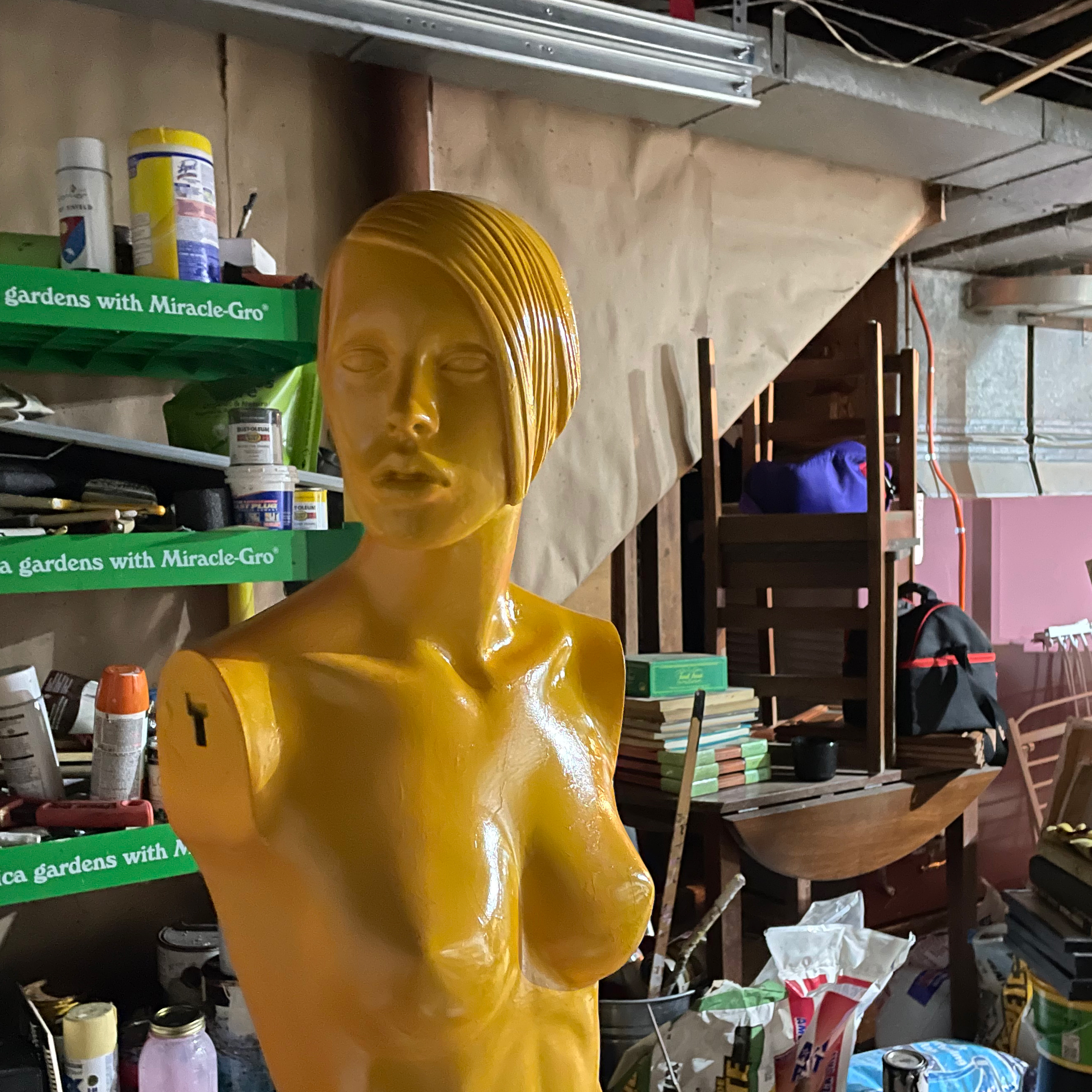 naked mannequin painted gold in messy garage